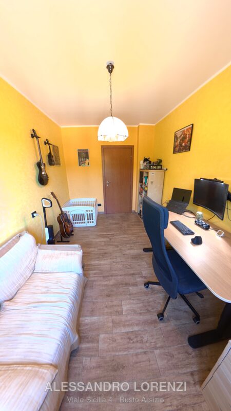 Studio arredato con chitarre a parete, scrivania e divano letto